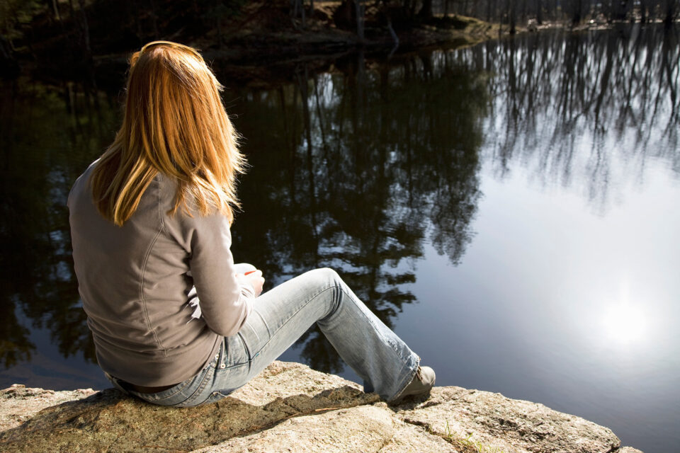 woman sitting alone near river